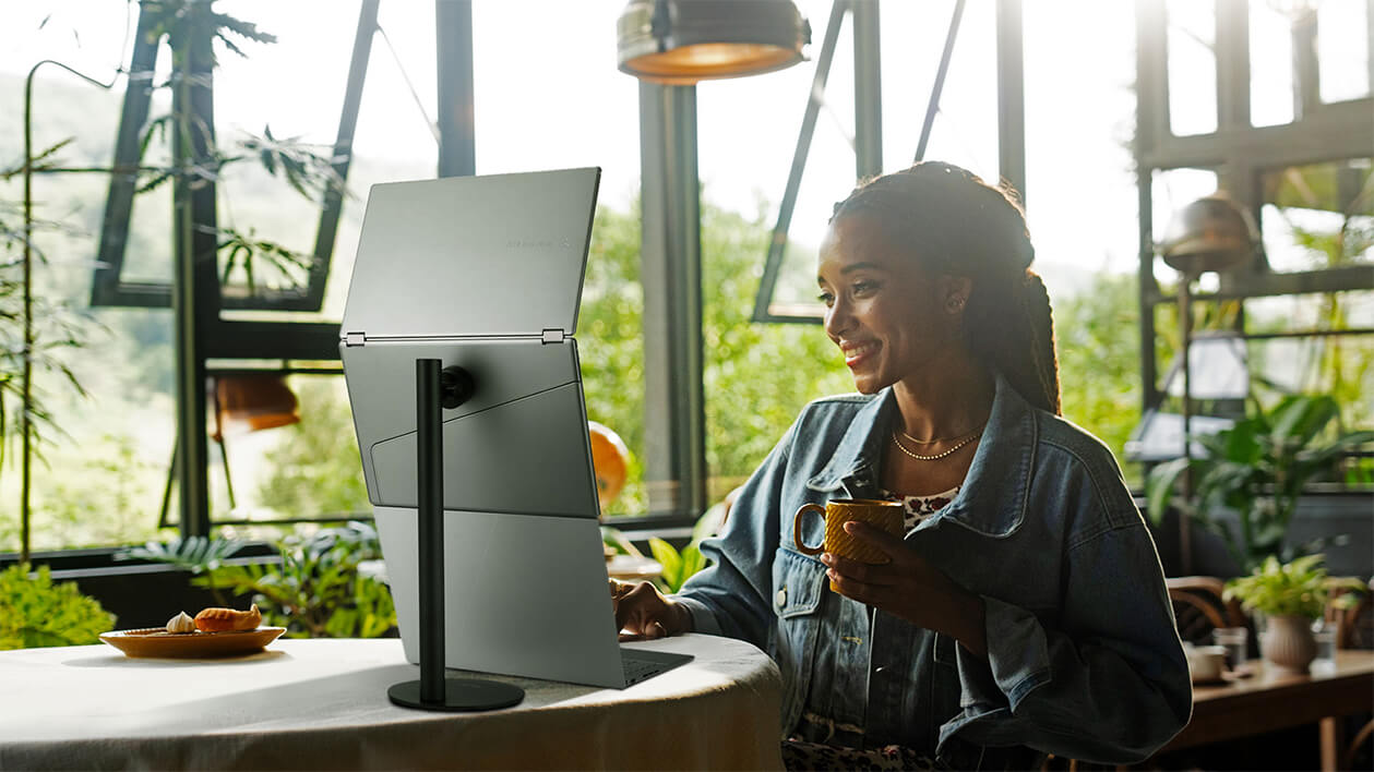 Zeigt ein junges Mädchen bei der Arbeit an einem komfortablen Dual-Setup mit einem Laptop, der an den tragbaren Monitor MQ149CD angeschlossen ist, der auf dem Stativständer MTS02D für tragbare Monitore befestigt ist, Anzeige im Querformat
