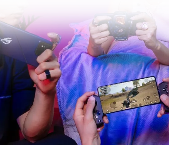 People gaming on ROG Phone with cooler attachment and handheld console showing action game on screen